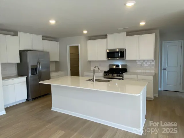 a kitchen with a sink a refrigerator and a stove top oven