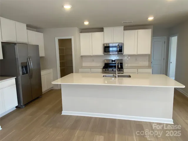 a kitchen with stainless steel appliances a refrigerator a sink a stove a microwave and wooden floor
