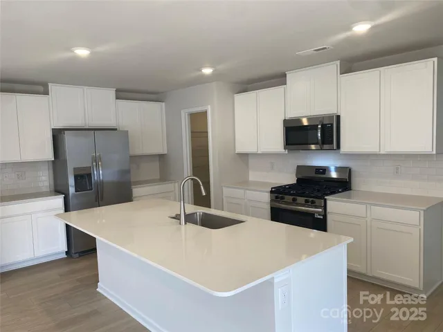a kitchen with stainless steel appliances a sink stove refrigerator and cabinets
