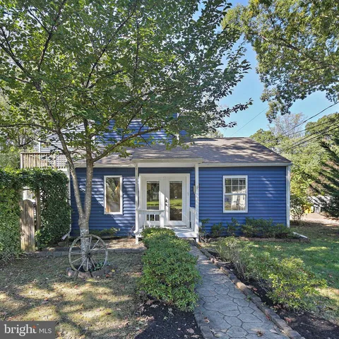 a view of a brick house with a yard plants and large tree