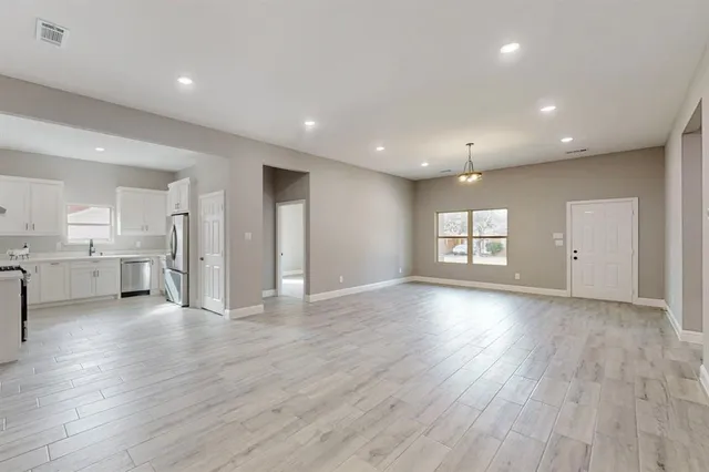 a view of an empty room with a window and wooden floor