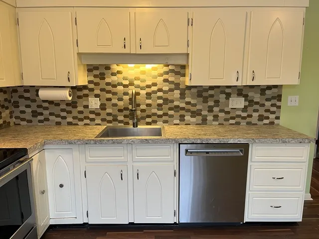 a kitchen with stainless steel appliances granite countertop white cabinets and a stove