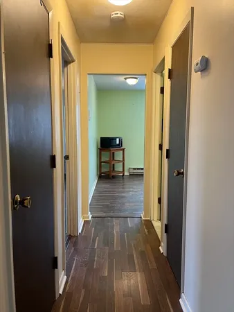 a view of a hallway with wooden floor and furniture