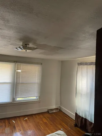 an empty room with wooden floor cabinet and windows
