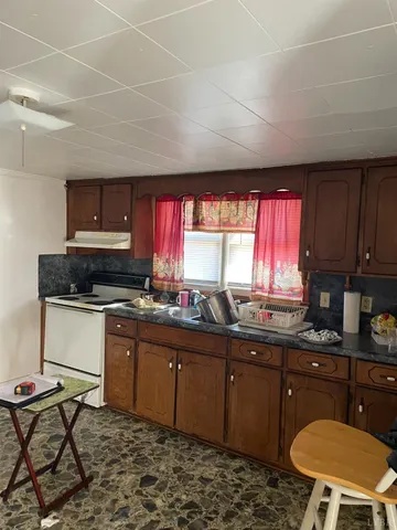 a kitchen with a sink a stove a window cabinets and stainless steel appliances