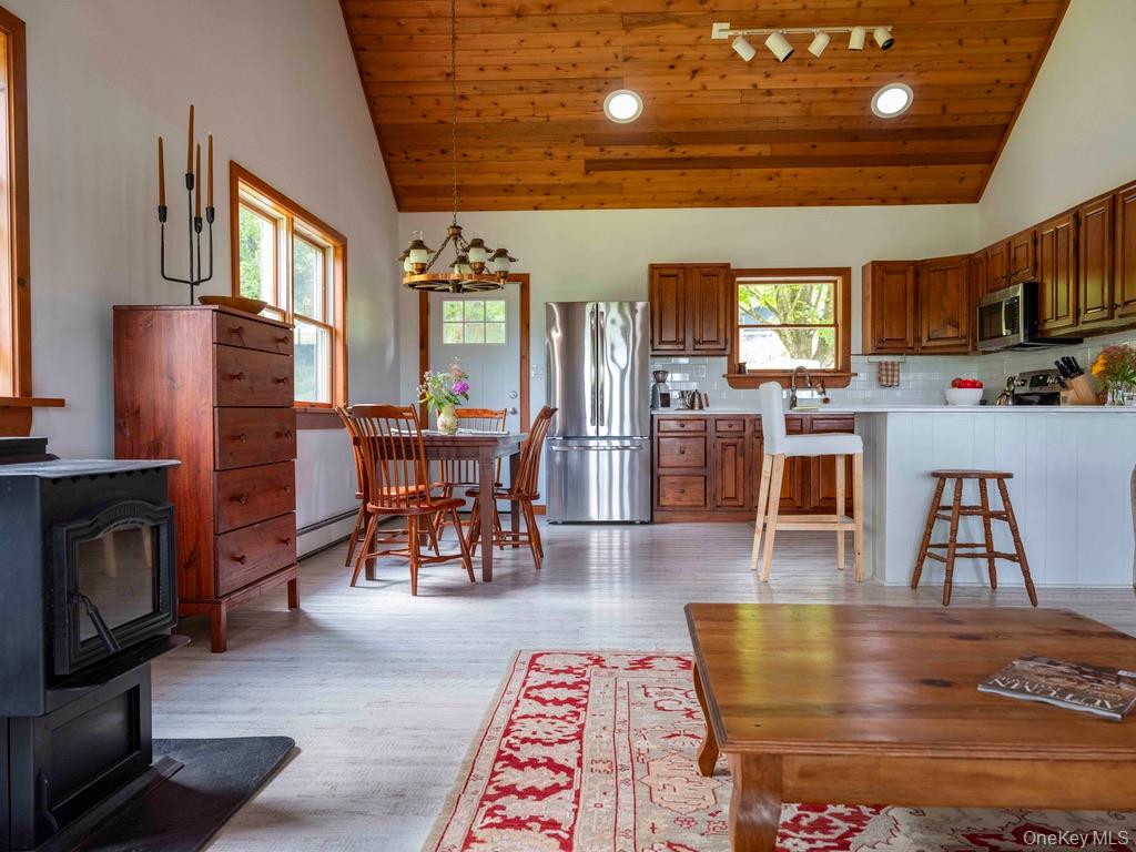 284 Ridge Road Hamden, NY 13782 - Photo 8 of 44 Living room with pellet stove and vaulted wood ceiling looking into kitchen. Mix and mingle with family and friends