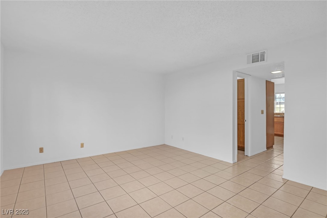 7030 Burcot Avenue, Unit F108 Las Vegas, NV 89156 - Photo 3 of 18 Empty room with light tile patterned floors and a textured ceiling