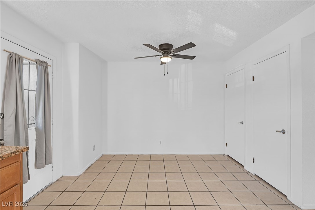 7030 Burcot Avenue, Unit F108 Las Vegas, NV 89156 - Photo 7 of 18 Unfurnished room featuring ceiling fan, light tile patterned floors, and a textured ceiling