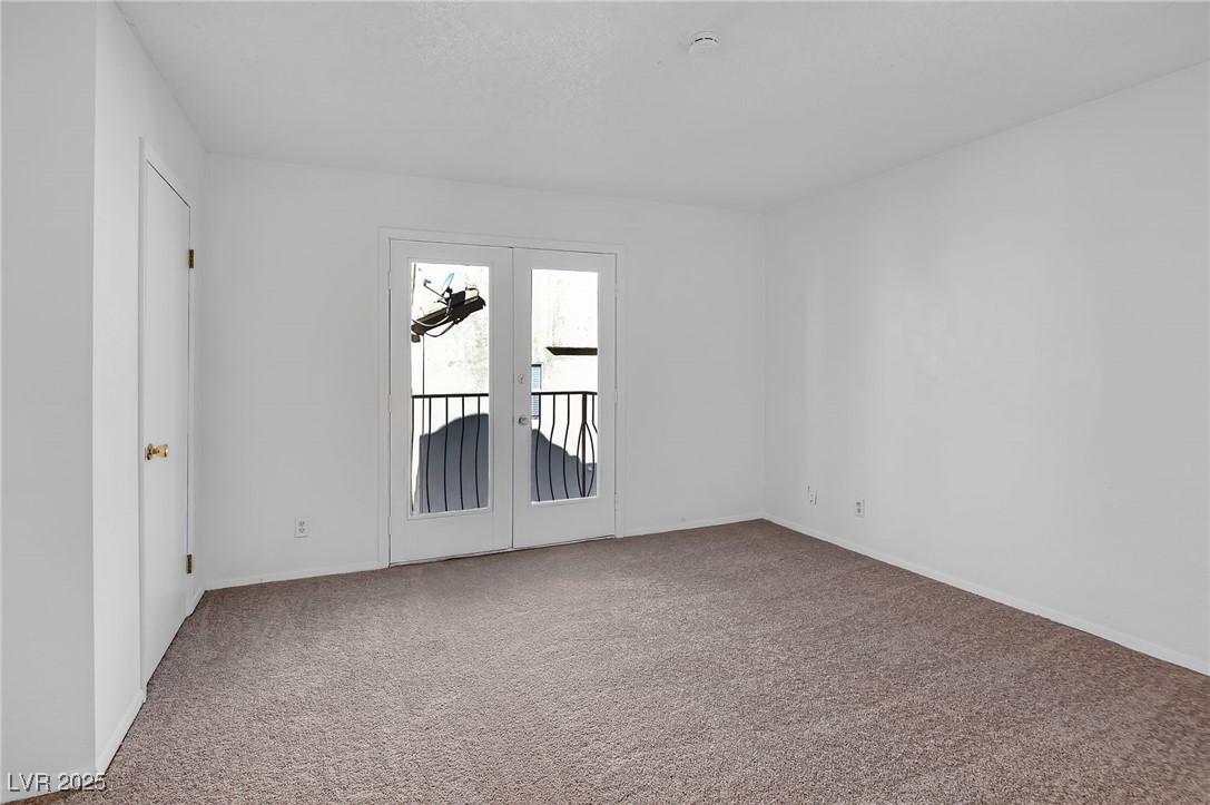 7030 Burcot Avenue, Unit F108 Las Vegas, NV 89156 - Photo 9 of 18 Carpeted spare room featuring french doors and baseboards