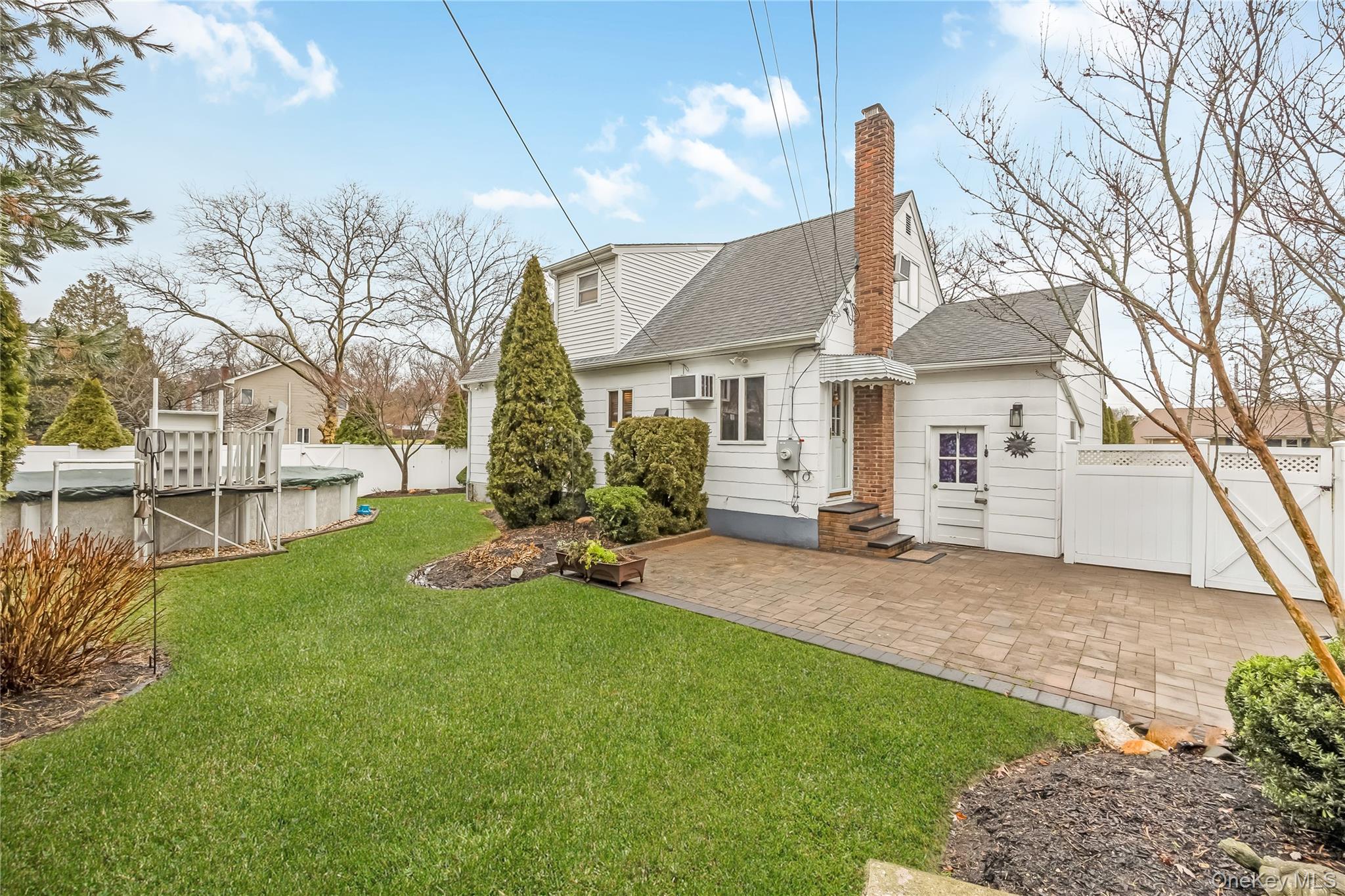 10 Roxbury Street Farmingdale, NY 11735 - Photo 23 of 25 a view of a white house next to a yard with big trees