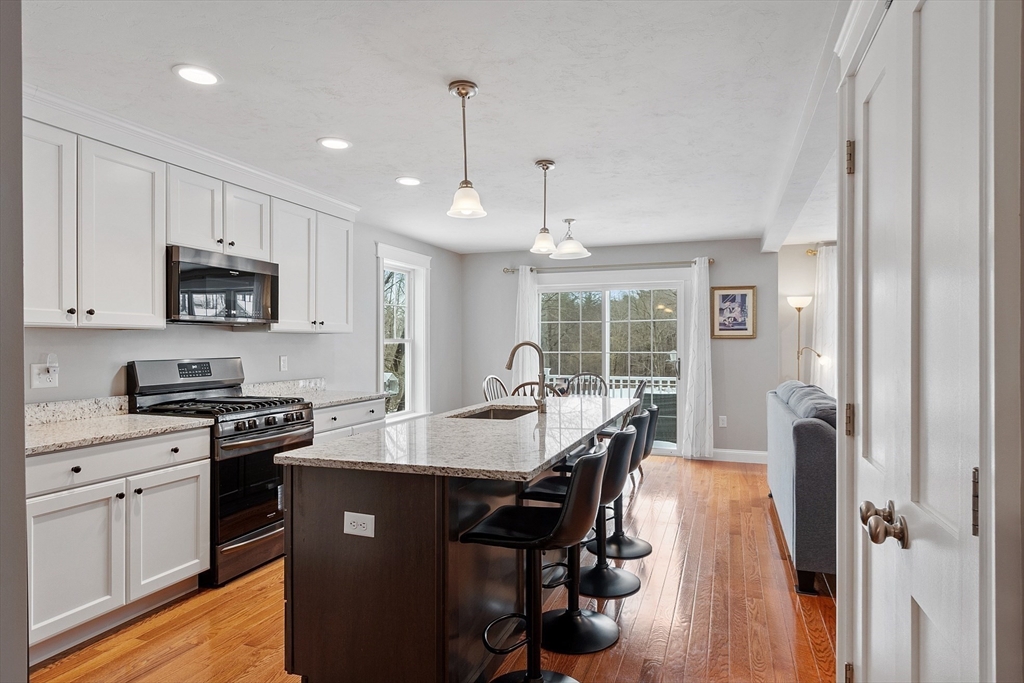 4 Scotch Pine Farm Way, Unit 1 Pepperell, MA 01463 - Photo 4 of 35 a kitchen with stainless steel appliances granite countertop a sink a stove a refrigerator cabinets and a dining table