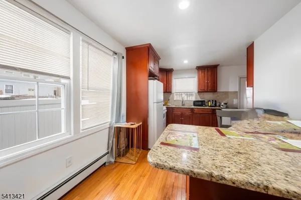 a kitchen with granite countertop a stove a sink a refrigerator and wooden cabinets