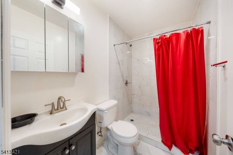853 Rebecca Place Elizabeth, NJ 07201 - Photo 9 of 22 a bathroom with a sink a toilet and shower curtain