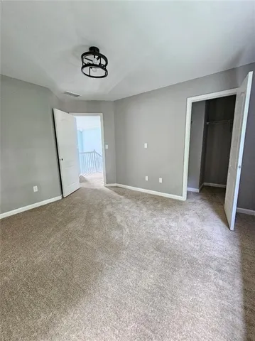 an empty room with a chandelier fan and windows