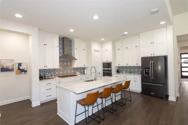 a kitchen with stainless steel appliances kitchen island granite countertop a refrigerator and a stove top oven