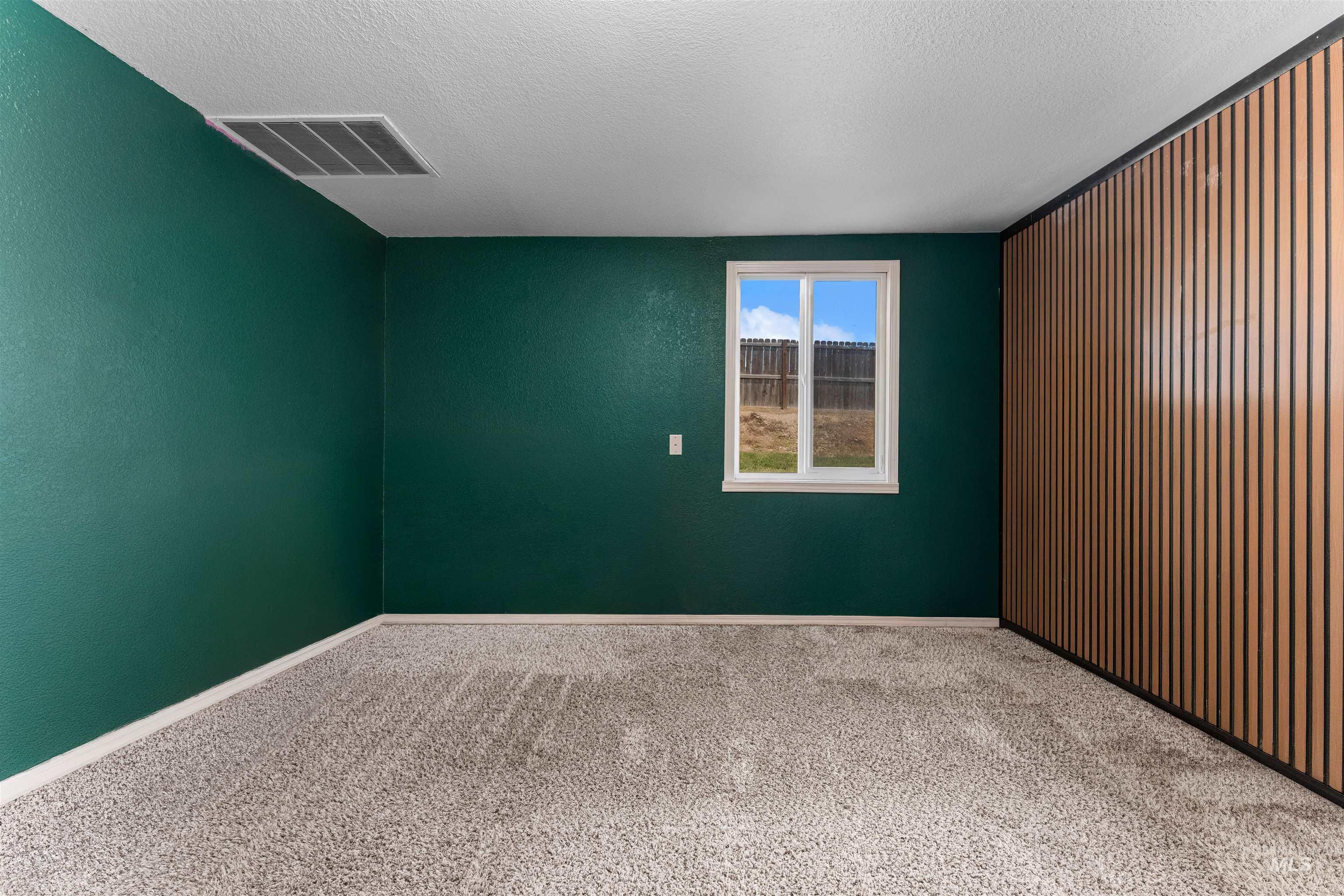 17441 Upper Pleasant Ridge Road Caldwell, ID 83607 - Photo 21 of 40 Room featuring a window, wood-finish accent wall, and textured green walls