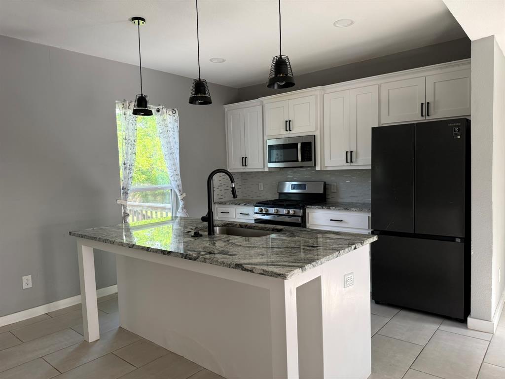 a kitchen with kitchen island granite countertop a sink a counter space appliances and cabinets
