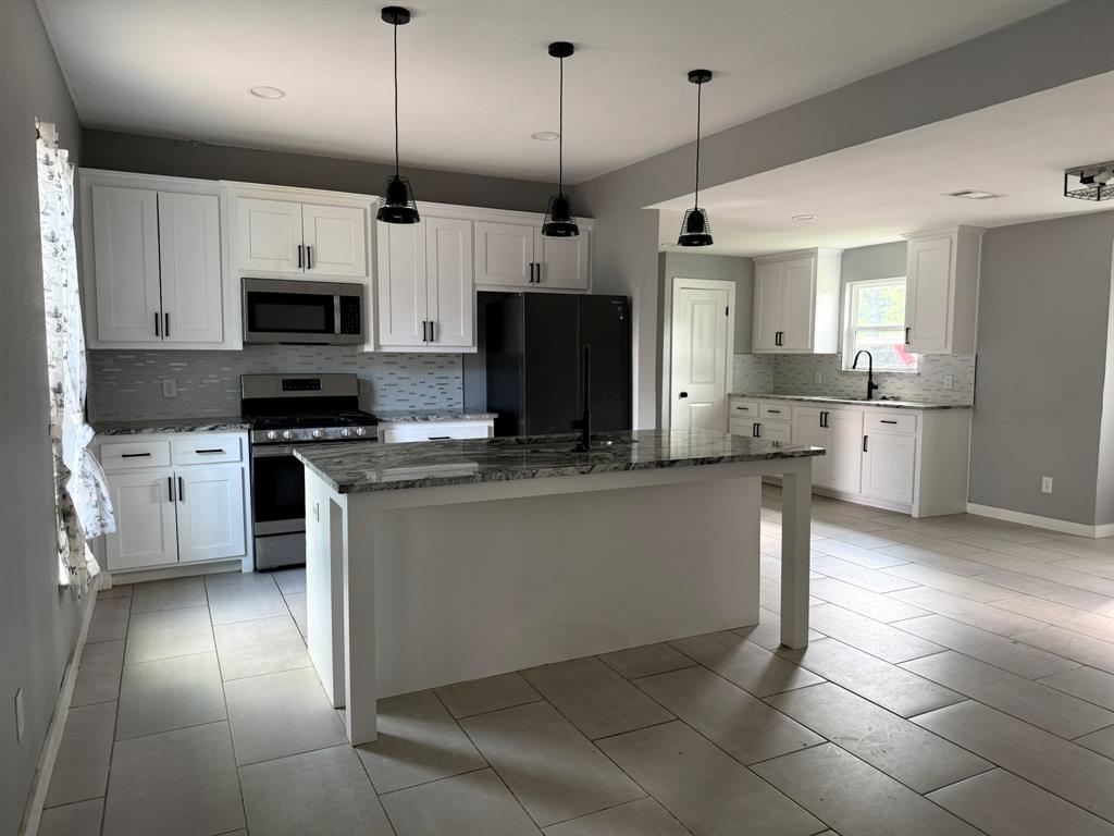 202 4th Street Joshua, TX 76058 - Photo 3 of 39 a kitchen with stainless steel appliances granite countertop a stove a sink and a refrigerator