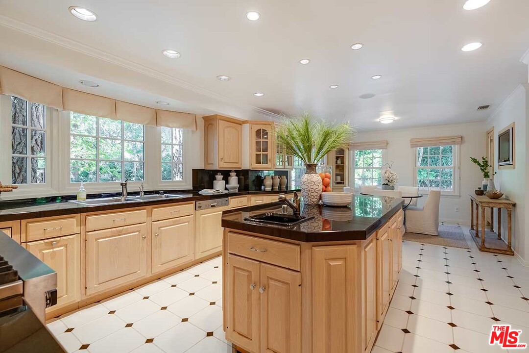 11610 Bellagio Road Los Angeles, CA 90049 - Photo 18 of 46 a kitchen with stainless steel appliances kitchen island granite countertop a sink and cabinets
