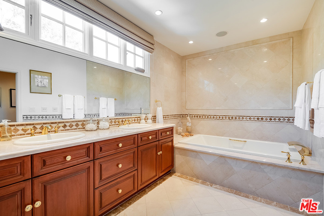 11610 Bellagio Road Los Angeles, CA 90049 - Photo 30 of 46 a bathroom with a granite countertop tub sink and mirror