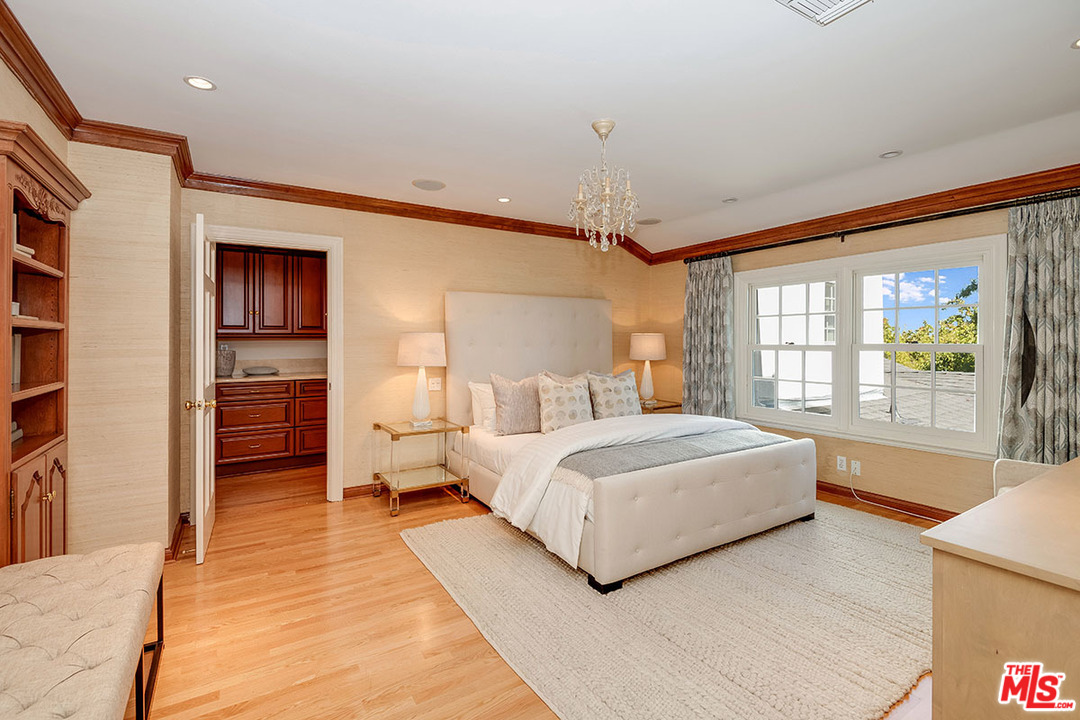 11610 Bellagio Road Los Angeles, CA 90049 - Photo 32 of 46 a spacious bedroom with a large bed and a chandelier