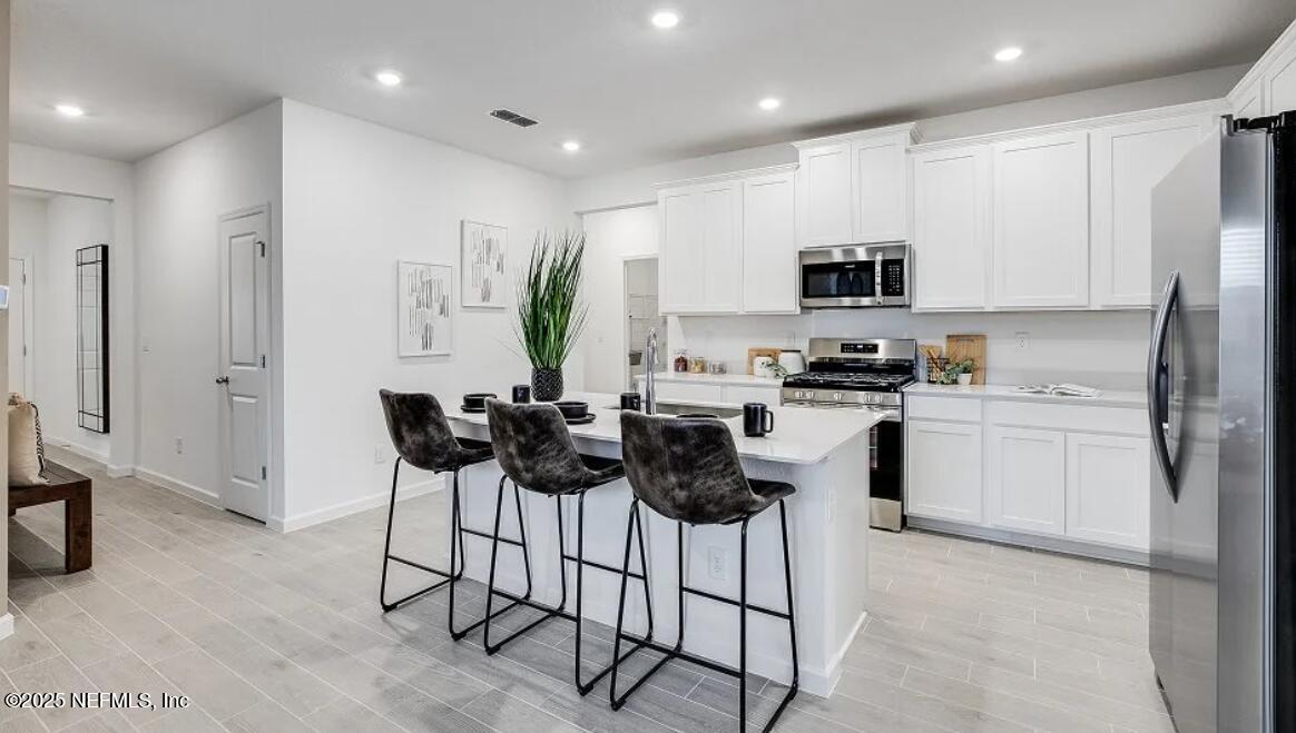 73 Whitmore Drive St. Augustine, FL 32092 - Photo 23 of 30 a kitchen with white cabinets and stainless steel appliances
