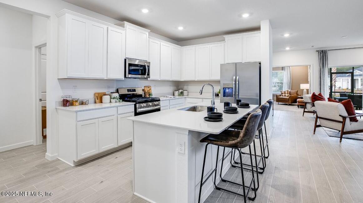 73 Whitmore Drive St. Augustine, FL 32092 - Photo 24 of 30 a kitchen with stainless steel appliances a microwave a stove a sink a refrigerator and white cabinets with wooden floor