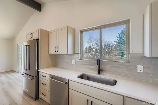 a kitchen with stainless steel appliances a sink a refrigerator and window
