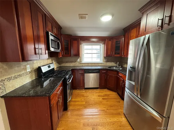 a kitchen with granite countertop stainless steel appliances a refrigerator stove top oven and sink