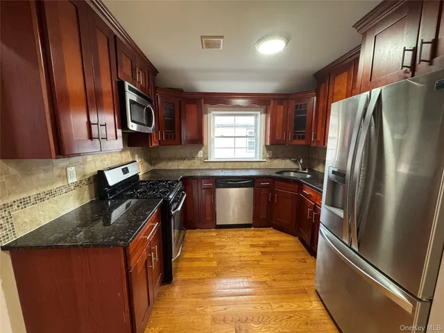 a kitchen with granite countertop stainless steel appliances a refrigerator stove top oven and sink