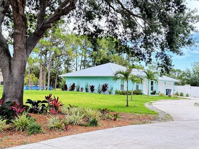 a view of a house with garden and a tree