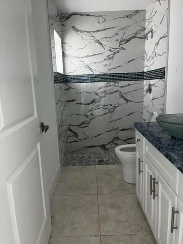 a bathroom with a granite countertop sink a toilet and a shower