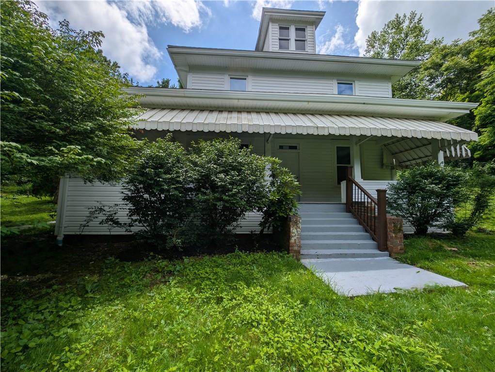 a view of a house with a yard plants and large tree