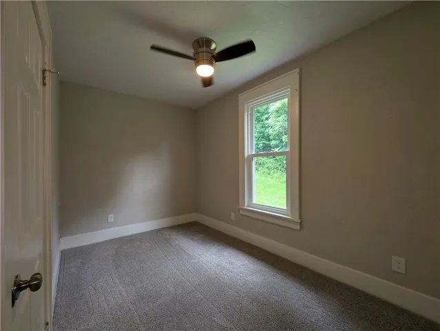 an empty room with a window and a ceiling fan