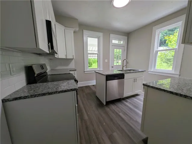 a kitchen with granite countertop a sink a counter space appliances and cabinets
