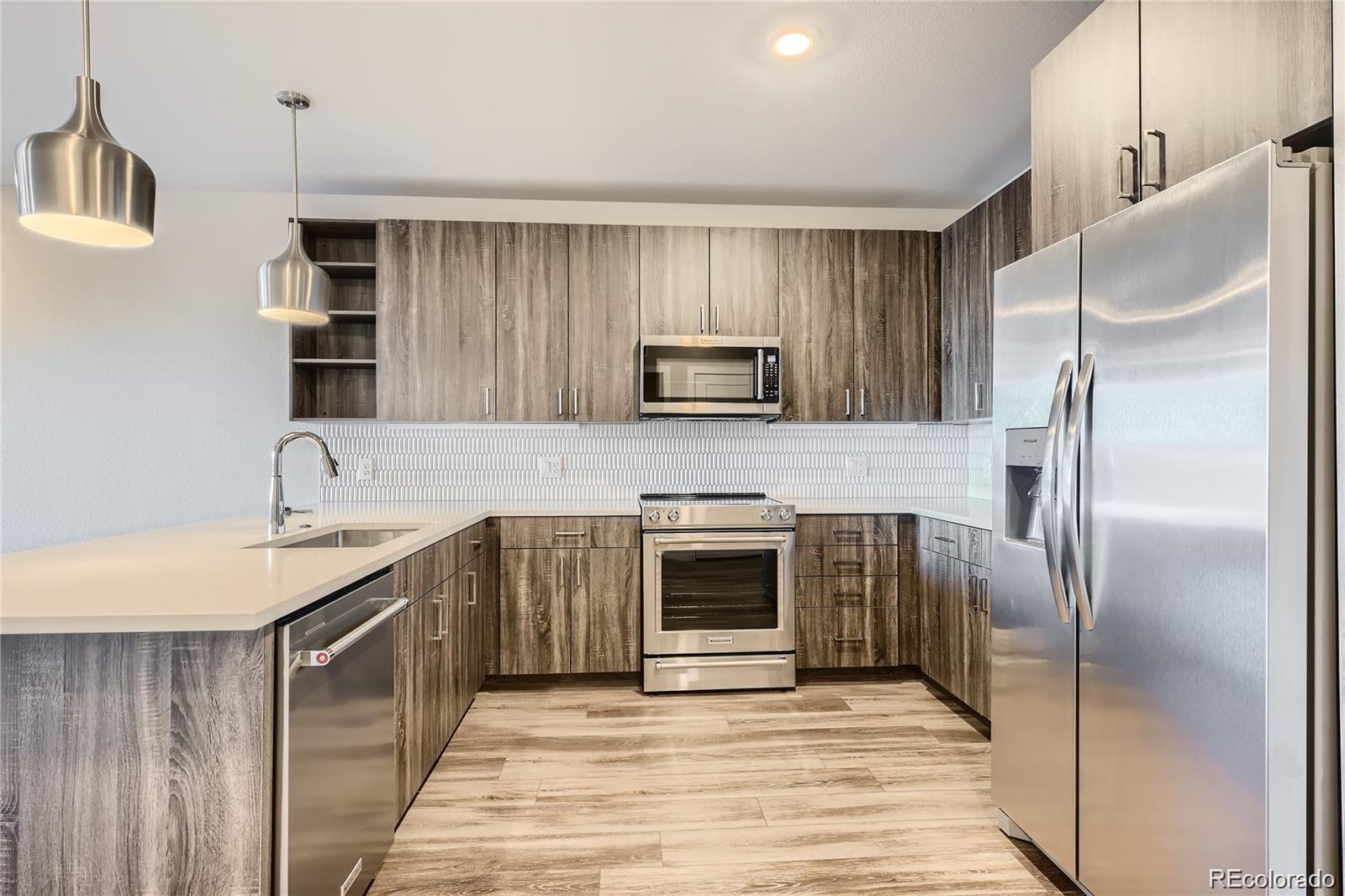 a kitchen with stainless steel appliances granite countertop a refrigerator a stove and a sink with wooden floor