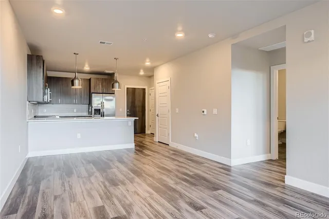 a view of kitchen with kitchen island wooden floor center island and stainless steel appliances