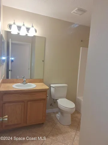 a bathroom with a granite countertop toilet a sink and a mirror
