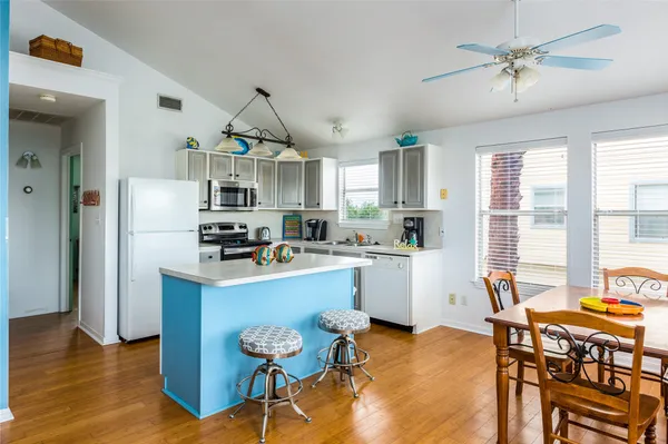 a kitchen with stainless steel appliances a stove a refrigerator a sink a dining table and chairs with wooden floor