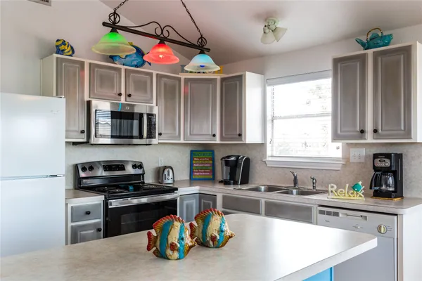 a kitchen with stainless steel appliances granite countertop a sink a stove and a wooden cabinets