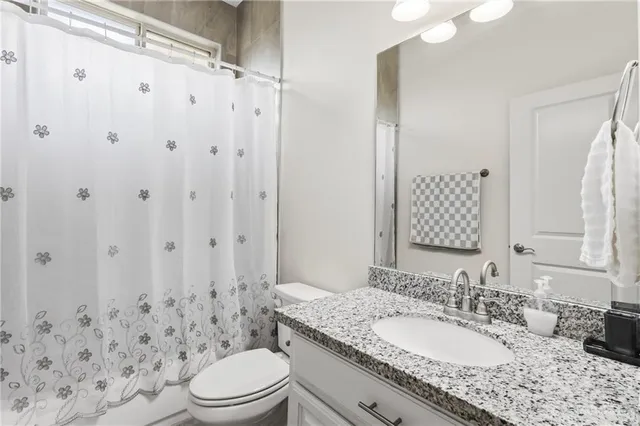 a bathroom with a granite countertop sink toilet a mirror a vanity and shower