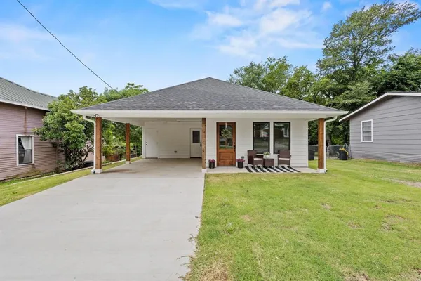 a view of a house with table and chairs next to a yard