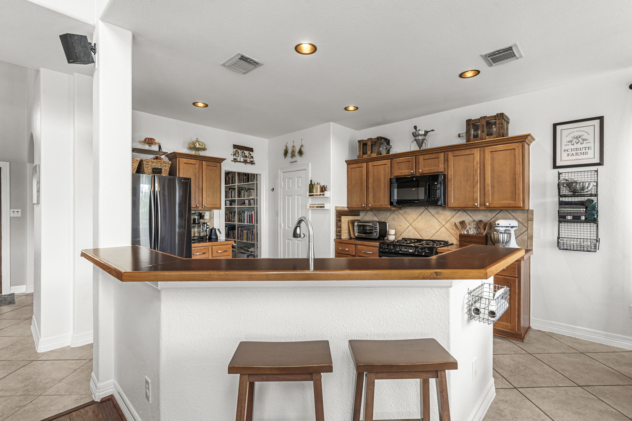 454 Fall Circle Kyle, TX 78640 - Photo 11 of 39 A well-equipped kitchen features a breakfast bar, recessed lighting, and tile flooring.