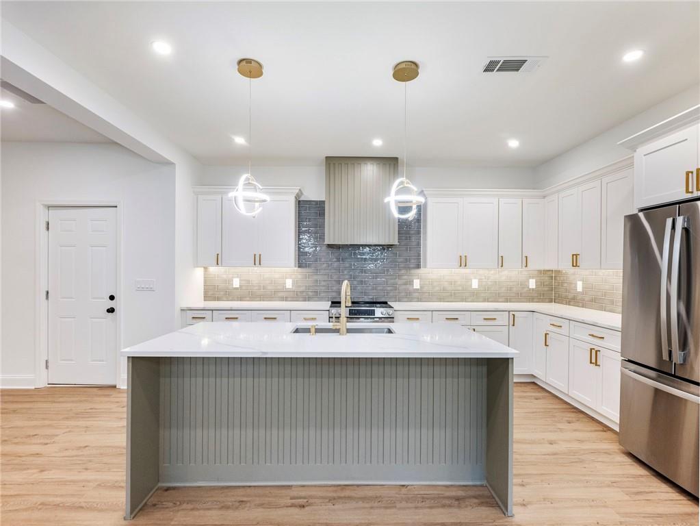 a view of a kitchen with kitchen island a sink stainless steel appliances and cabinets