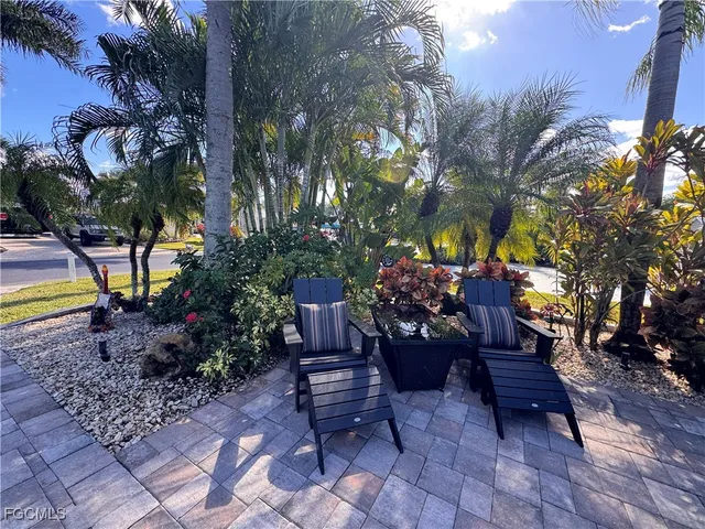 a patio with a table and chairs under an umbrella with a barbeque