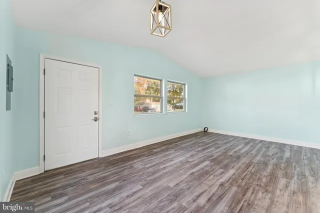 an empty room with wooden floor closet and windows