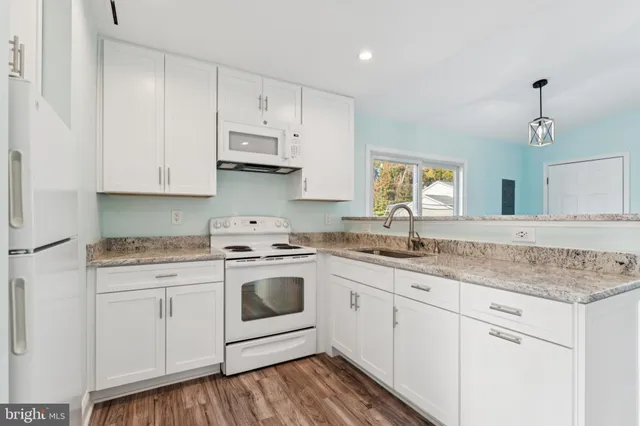 a kitchen with granite countertop white cabinets and white appliances