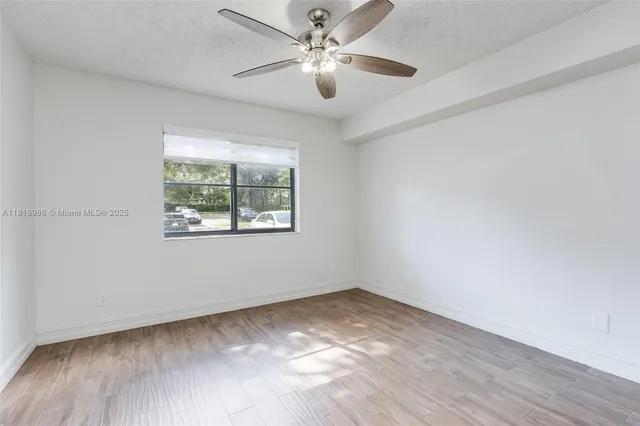 an empty room with a window and a ceiling fan