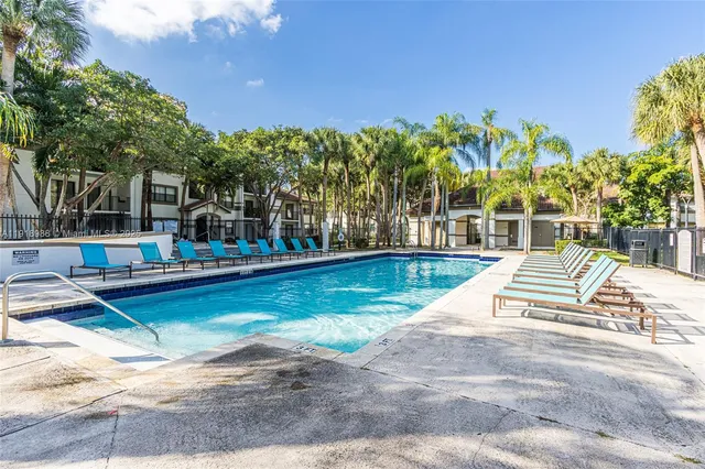 a view of swimming pool with lawn chairs and plants