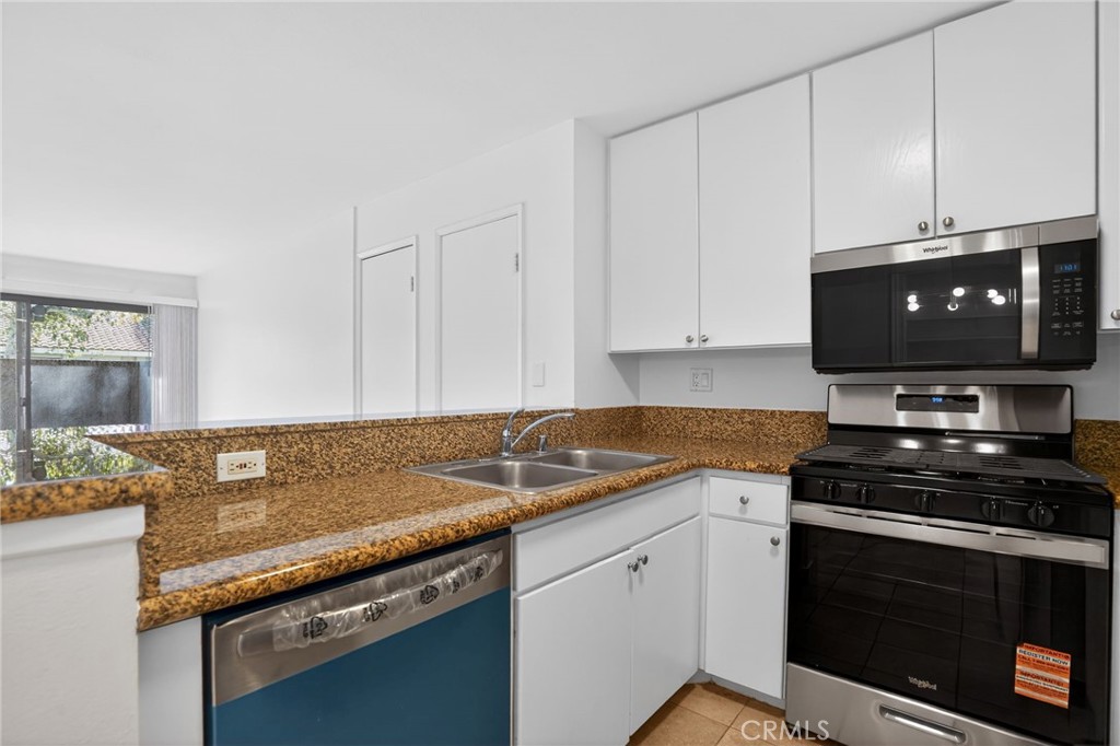 18808 Mandan Street, Unit 309 Canyon Country, CA 91351 - Photo 6 of 19 a view of kitchen with granite countertop white cabinets and black appliances
